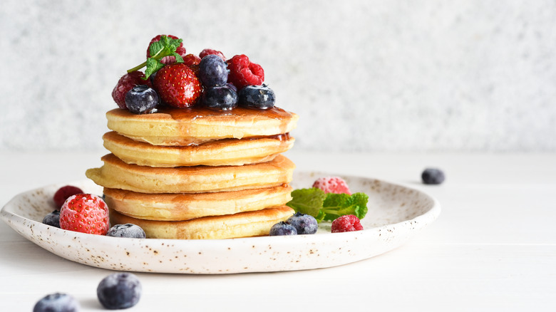 stack of fluffy pancakes on a plate topped with berries