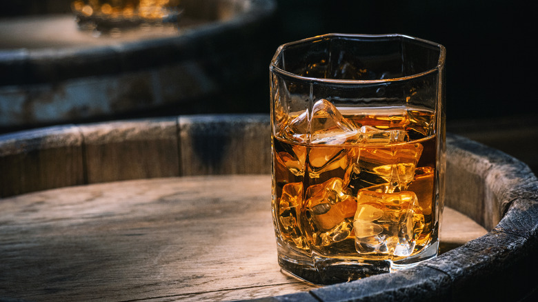 Whisky on ice in glass on barrel