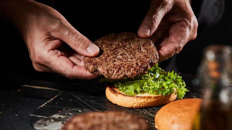 Hamburger patty being placed on bun