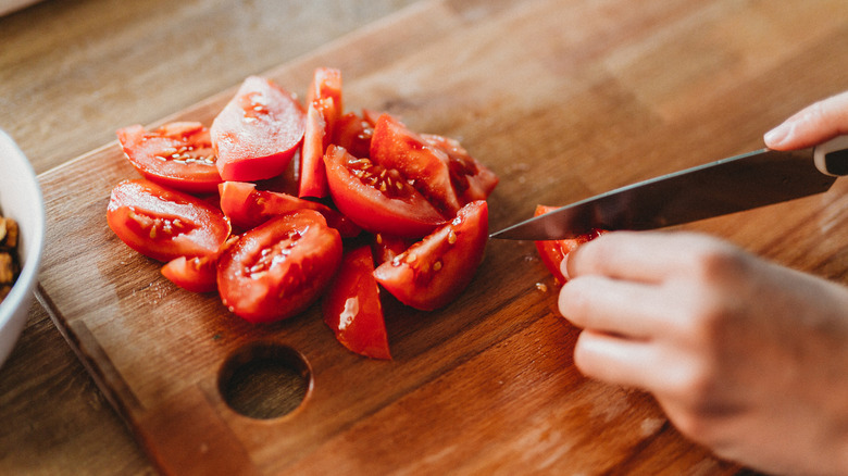 person cutting tomatoes