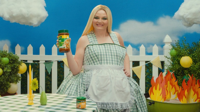 Comedian Meg Stalter posing with Knorr products in artificial backyard environment.