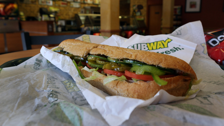A Subway sandwich on a wrapper on a table. 
