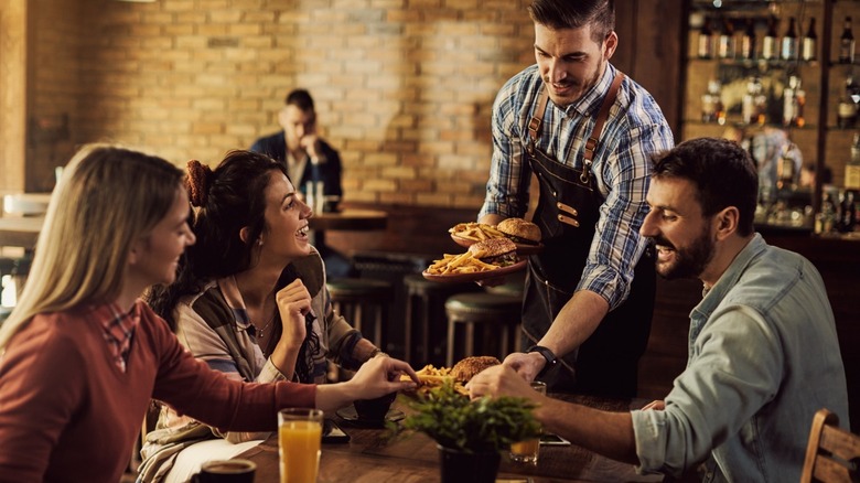 Waiter serving a table burgers