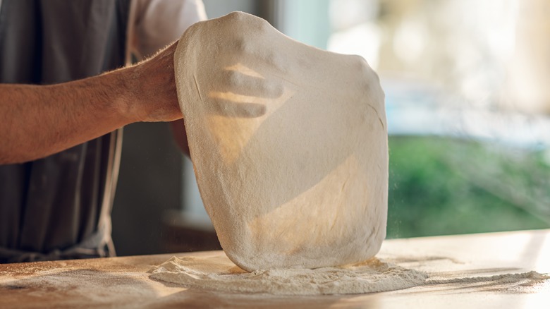 hands working raw pizza dough