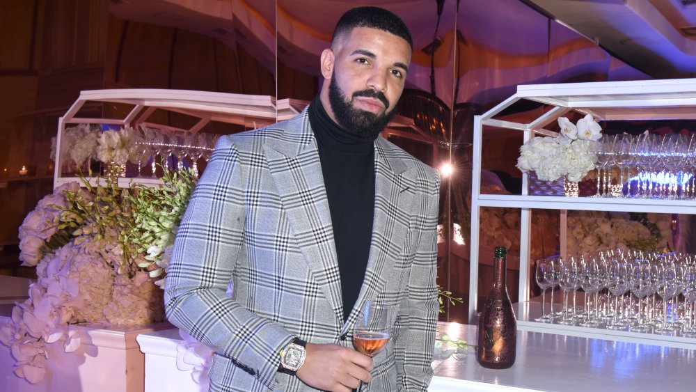 Drake enjoying himself at a party with a glass of rose