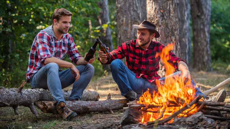 Guys drinking beers by a fire