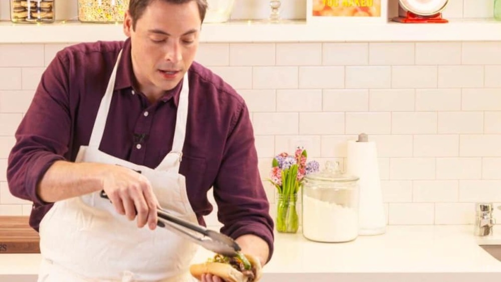 Jeff Mauro putting giardiniera on an Italian beef sandwich