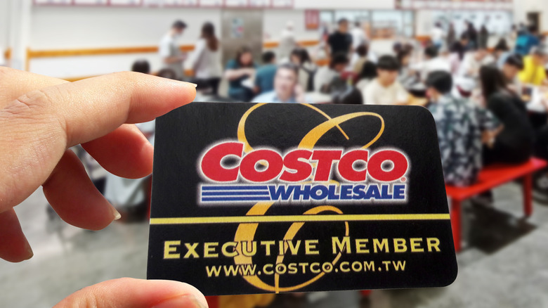 person holding Costco membership card in busy food court