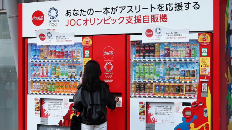 Woman standing at bottled drink vending machines in Japan