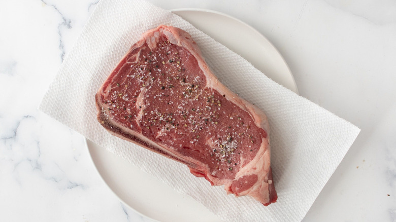 Raw steak seasoned with salt and pepper