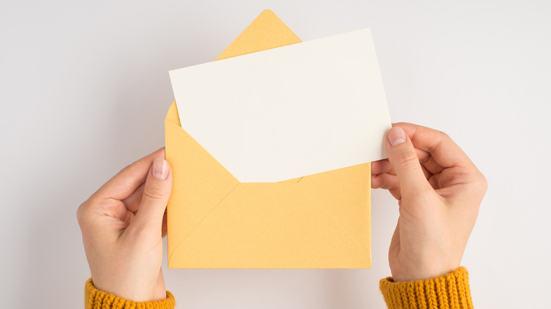 hands putting letter in envelope