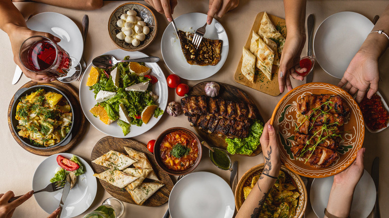 hands grabbing food from full table