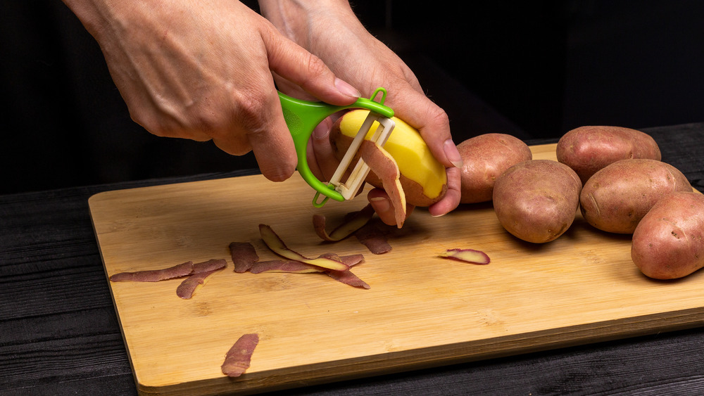 Hands holding a green vegetable peeler