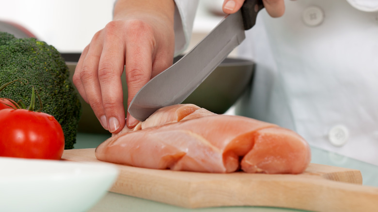 chef cuts chicken breast