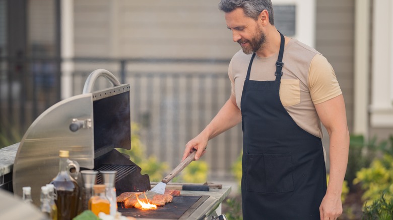 man flipping items on grill