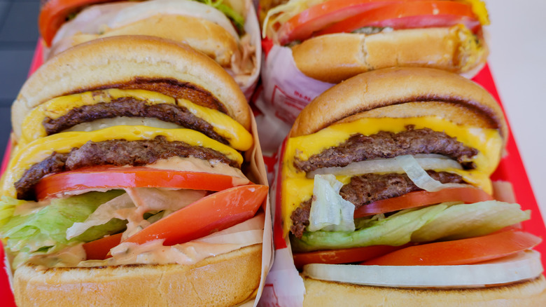 Close-up of numerous In-N-Out burgers with cheese, lettuce, onions, and tomatoes