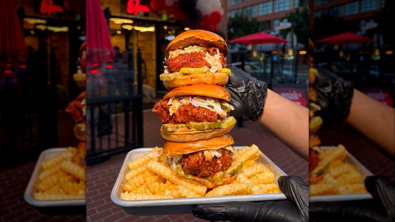 Three chicken sandwiches stacked on tray with French fries
