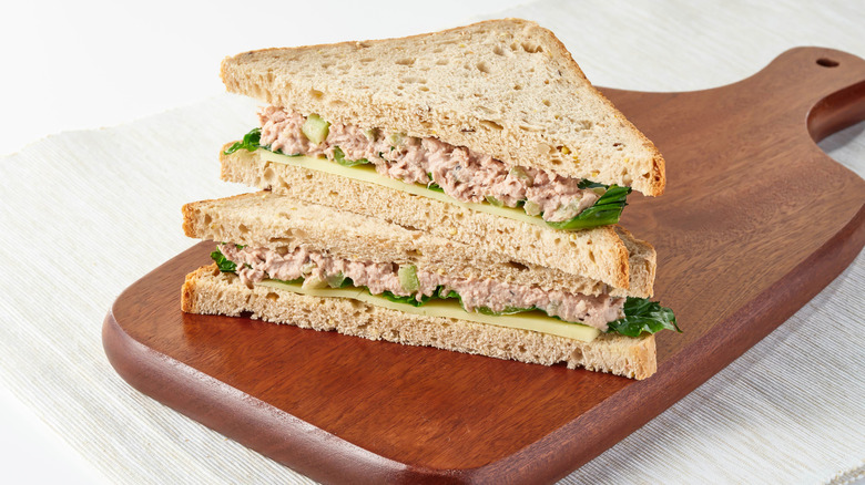 A sliced tuna sandwich on a wooden cutting board