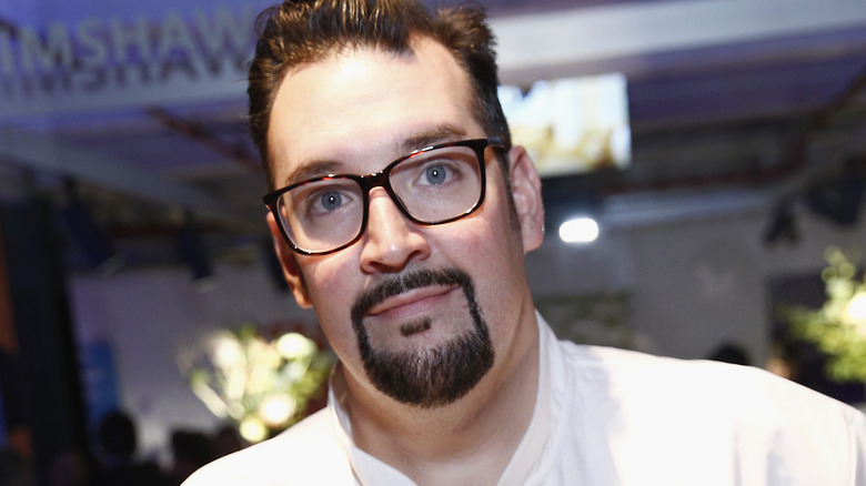 Michael Vignola looks forward in black framed glasses and a goatee