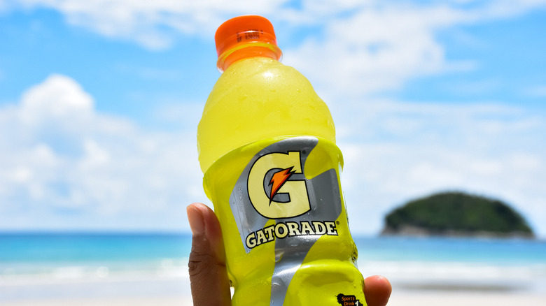 A bottle of lemon/lime Gatorade with beach in background.