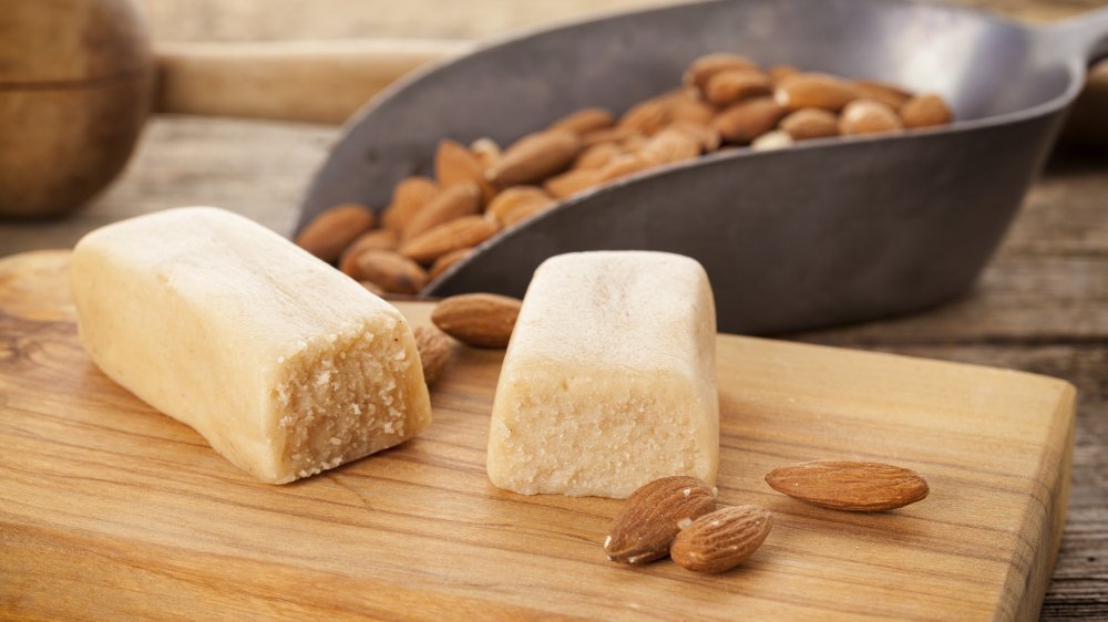 Bars of marzipan with almonds on cutting board