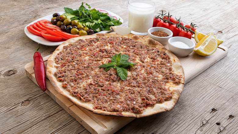 Lahmacun on a wooden board with vegetables