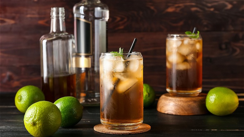 Texas tea in cocktail glass surrounded by limes and a label-free bottle of bourbon