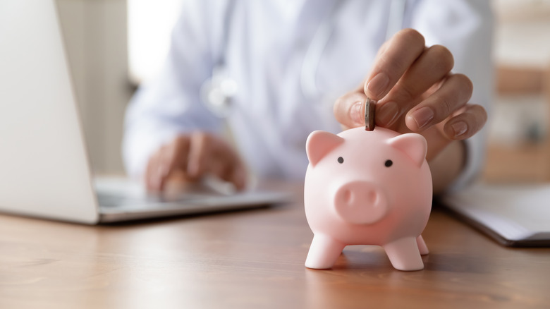 Person dropping coin into piggy bank