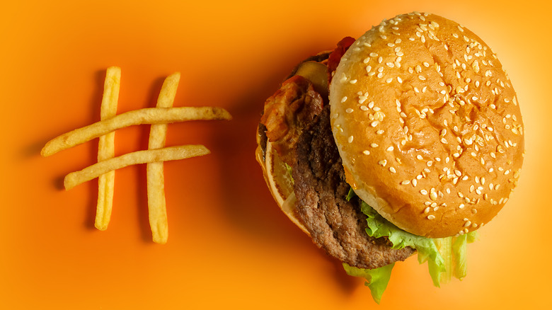 A Big Mac with fries against a yellow background