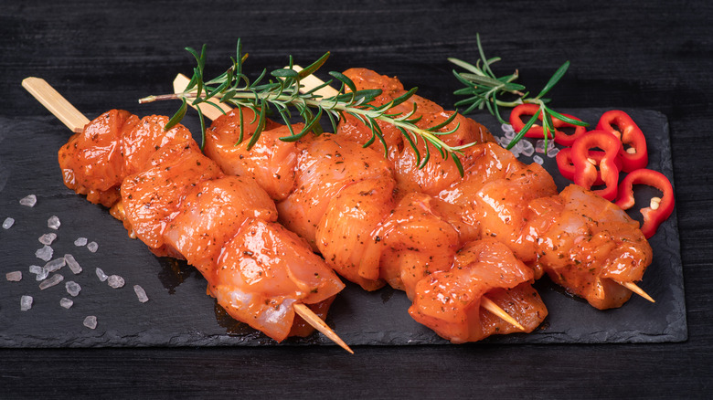 Chicken skewers in a marinade on a black plate