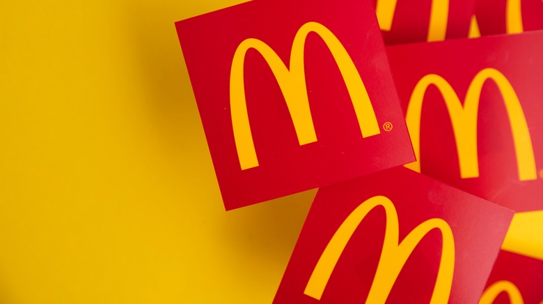 Several McDonald's golden arches on red cards against a gold background 