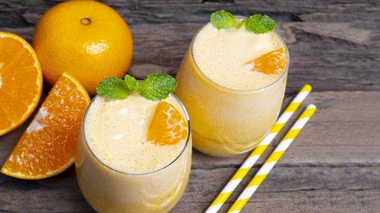 orange smoothies with straws and oranges