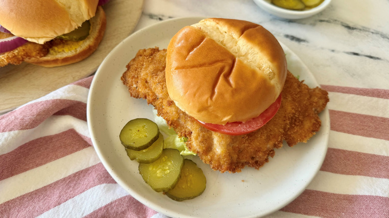 Hoosier pork tenderloin sandwich on plate with pickles