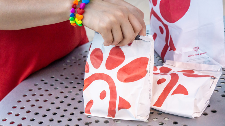 Hand with a rainbow bracelet holding a Chick-fil-a bag