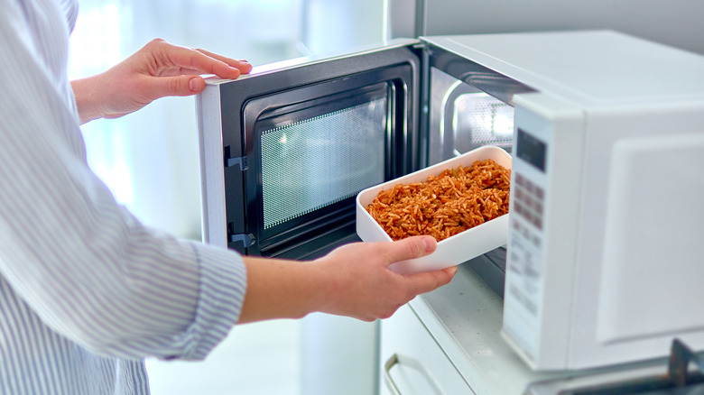 person warming up a meal in a microwave