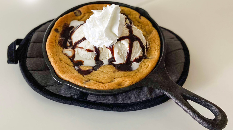 A mini cast iron skillet cookie topped with ice cream and toppings.