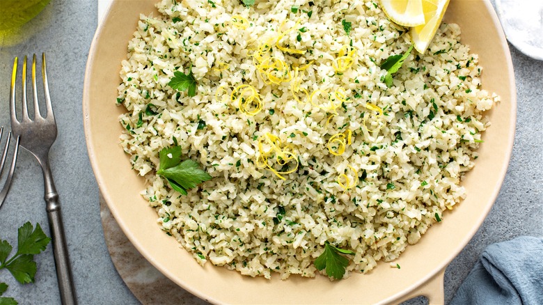 Freshly cooked cauliflower rice with herbs and lemon served in the pan.