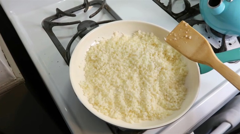 Cauliflower rice cooking in a pan.