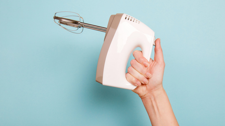 A hand holding a hand mixer up in the air
