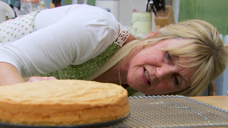 Nancy of "Great British Baking Show" leaning down to check on a cake