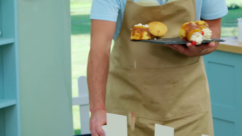 Dave holding his cakes as they fall on "The Great British Baking Show"