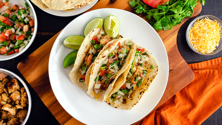 A styled shot of a plate of tacos surrounded by fresh ingredients