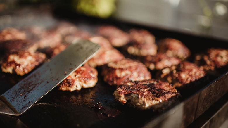 Burger patties cooking on flat-top grill