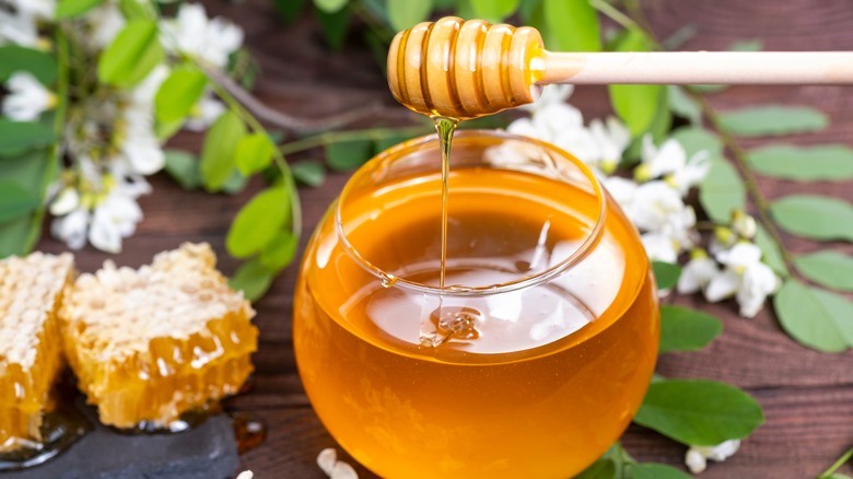 Honey in jar with honeycomb and flowers
