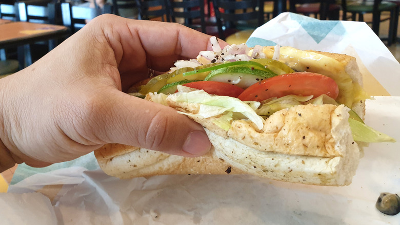 hand holding Subway tuna sandwich with the wrapper underneath