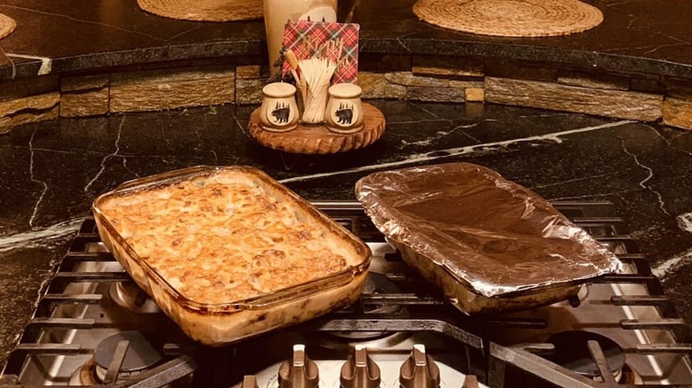 two casserole dishes of Connecticut beef supper sitting on a stovetop, one covered and one uncovered