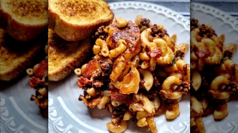 Serving of Johnny Marzetti on a white plate with garlic bread to the side