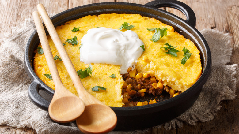 tamale pie in a cast iron dish with a slice missing