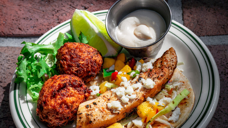 conch fritters served with a fish taco and dipping sauce on plate