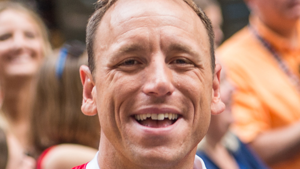 Closeup of Joey Chestnut smiling with people in background